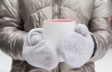 Fototapeta na wymiar Winter girl in gloves holds a mug on a cold winter day. Place for inscription