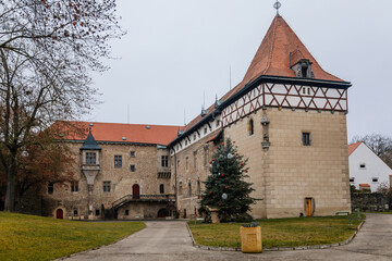 Fototapeta na wymiar Fortified medieval stronghold, Moated gothic castle at romantic style, National cultural landmark with Christmas tree in winter day, Budyne nad Ohri, Bohemia, Czech Republic