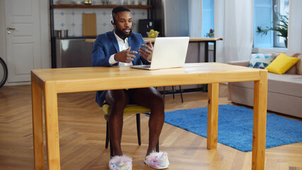 African businessman having video call on laptop working in underwear at home office