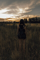 young woman watching the sunset among the dry herbs, sunset on dirt road, sunset on the road, sunset in the field, incredible sky, sky with clouds, golden hour