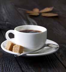 A cup of coffee on a wooden background. Morning hot coffee and cane sugar on a wooden table. A white coffee cup. Steam.Espresso