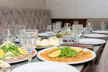 Festive table setting, family dinner with served italian antipasti - marinated salmon, hamon, Carpaccio, pear, basil. Tablescape.