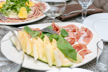 prosciutto di parma ham with melon served on white plate at the restaurant