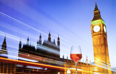 a glass of wine against Big Ben and Westminster (parliament) Bridge over Thames river at dusk,...