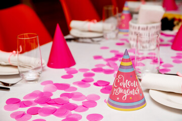 A beautiful set table for a children's birthday. Empty plates with cutlery and tops with the words 'Happy Birthday'.