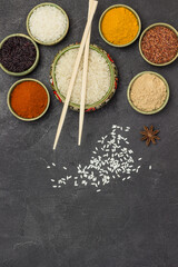 Fototapeta na wymiar Different types of rice and dry spices in bowls. Bamboo sticks