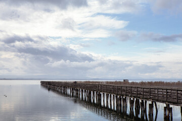 Fototapeta na wymiar Panorama of a wooden Pier on Trasimeno lake in a cloudy day, 