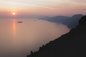 Fototapeta premium Panorama view of Mediterranean Sea at famous Amalfi Coast and the island of Capri, in beautiful pink evening light at sunset. Campania, Italy.