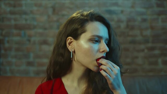 Close up of beautiful young woman taking lsd pill sitting on couch in nightclub