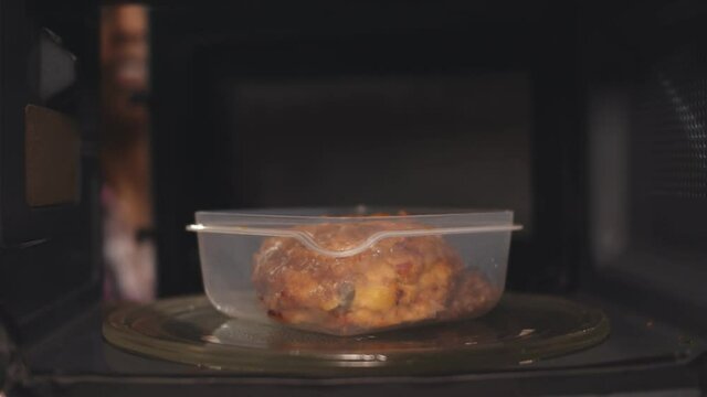 Afro-american woman using the microwave oven to heating food.