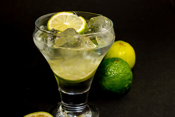 Alcoholic drinking Gin tonic. Close up on a black background. Lots of ice cubes and lime