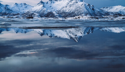 Clean cold sea reflecting majestic snowy mountains