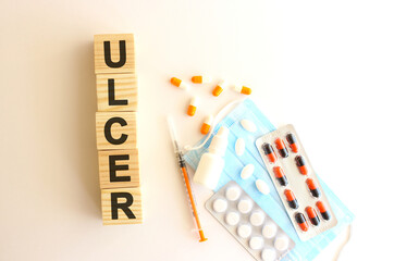 The word ULCER is made of wooden cubes on a white background. Medical concept.