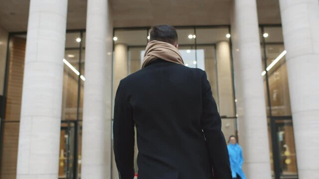 Back view of successful businessman entering business center