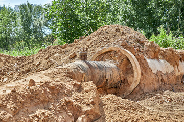 Fototapeta premium Reconstruction of the water supply network. An old water pipe in a reinforced concrete sleeve was dug out of the ground
