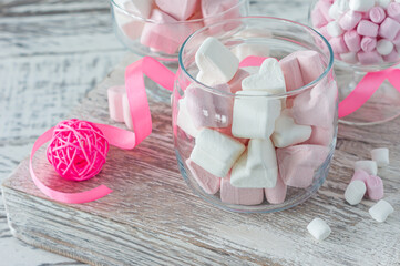 Bowl with tasty marshmallows and pink ribbon on white table, closeup