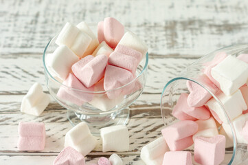 Assorted pink and white marshmallows in glass cups on wooden background. Heart shape marshmallow...