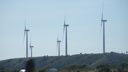 WIND GENERATORS IN A CLEAN ENERGY PARK ON TOP OF A HILL WITH THE SKY IN THE BACKGROUND