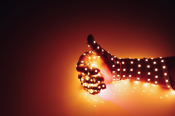 thumbs up hand covered with orange led lights, illuminated background