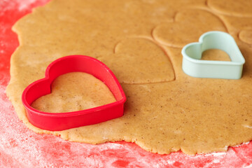 Dough for making heart shaped cookies on Valentines Day. Homemade pastry. Red and green plastic baking molds.