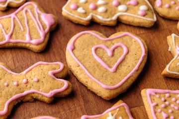 Two icing gingerbread hearts for Valentines Day on the wooden table with others homemade cookies.