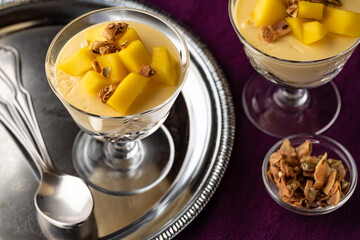 Close up of mango mousse dessert parfaits topped with granola ready for eating.