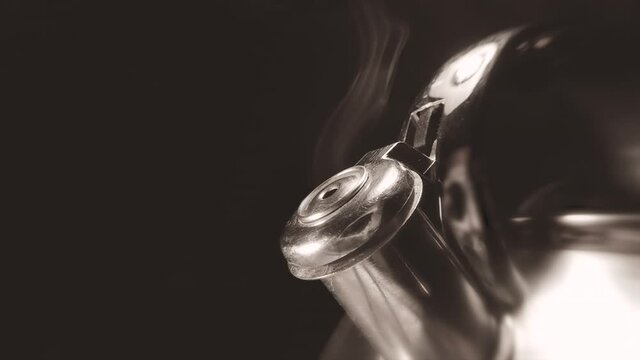 Kettle whistling closeup macro slow motion video, boiling kettle with steam texture on a black background. Vintage, grunge old retro style video.	