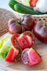 Making green salad with big ripe raddish-purple heirloom tomatoes Black Crimea