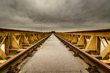 Old railway bridge over the river taken just before a winter storm