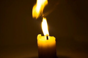 Photo of a burning candle with a yellow flame	