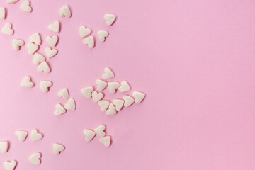 Sugar heart shaped sprinkles on pink background
