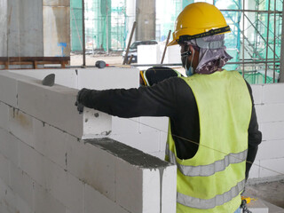 SEREMBAN, MALAYSIA -MARCH 17, 2020: Blockwork by construction workers at the construction site. Workers laying the AAC brick and stacked it together using mortar to form the wall. 
