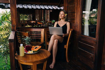 Cheerful woman resting with laptop in tropical resort