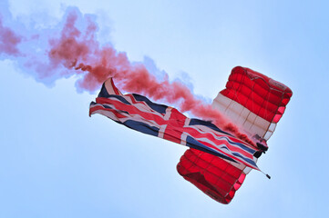 British Parachute Regiment parachutist descending to the ground with red smoke billowing and the Union Jack flag flying