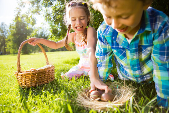 Cute boy and girl celebrating Easter, searching and eating chocolate eggs. Happy family holiday. Happy kids laughing, smiling and having fun. Beautiful spring sunny day in park