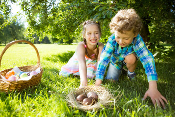 Cute boy and girl celebrating Easter, searching and eating chocolate eggs. Happy family holiday....