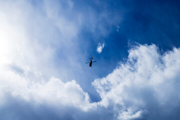 Naklejka na ściany i meble Blue sky with small helicopter flying into a thundercloud.