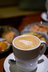 A cup of latte coffee and afternoon tea snacks