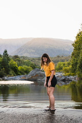 girl dressed in yellow enjoying and playing on a bridge near a river with a background of mountains