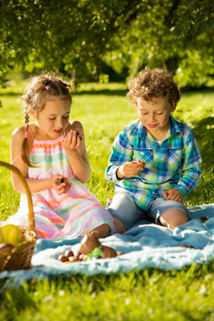 Cute boy and girl celebrating Easter, searching and eating chocolate eggs. Happy family holiday. Happy kids laughing, smiling and having fun. Beautiful spring sunny day in park