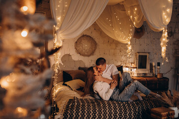 Obraz na płótnie Canvas The guy and the girl celebrate the New Year. A loving couple have fun on Christmas in a cozy studio setting. New Year's love story.