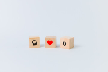Three wooden cubes on a white background with human symbols (brain, red heart, feet)