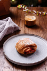 Puff pastry rolls with fruit and coffee on wooden table against Christmas tree. Danish pastries. Christmas breakfast