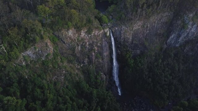 Close, aerial view of Ellenborough falls, New South Wales, NSW, Australia. Slow circular motion around waterfall during blue hour, dark and moody landscape wilderness