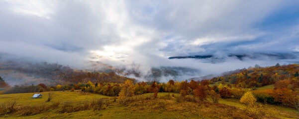 Fly over landscapes of green hills under a layer of white and fluffy clouds