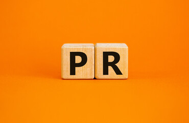 PR - public relations symbol. Wooden cubes with words 'PR, public relations' on beautiful orange...