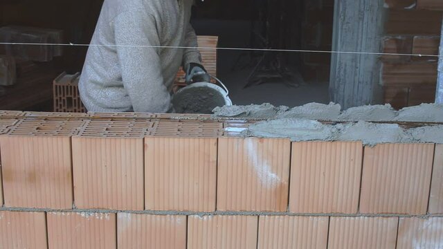 Industrial worker building exterior walls with orange bricks and mortar.