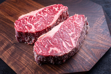 Modern style raw dry aged wagyu roast beef steak offered as top view on a wooden design board