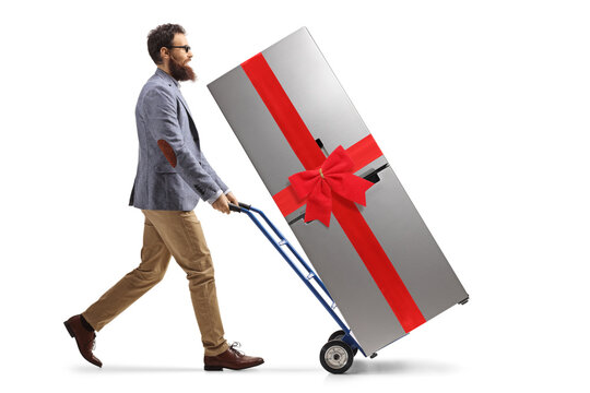 Bearded man pushing a hand truck with a fridge tied with a red ribbon