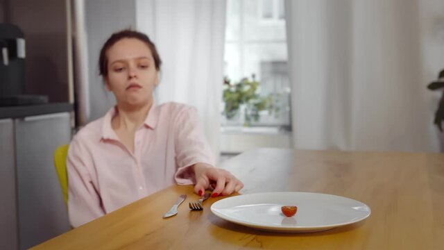 Anorexic woman feels dizzy depleted by severe diet trying to eat tomato